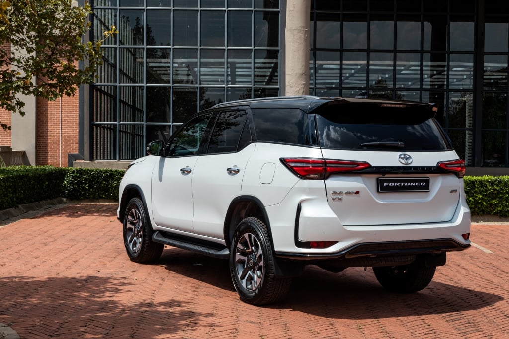 Rear 3 quarter view of a white Toytoa Fortuner in a office park parking lot