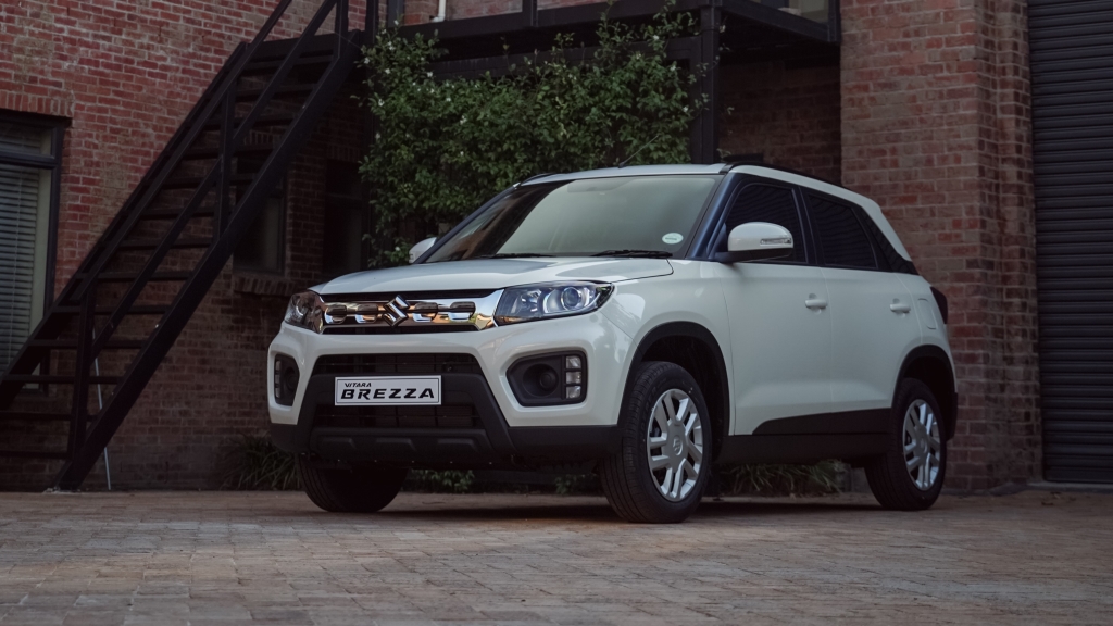 A white Suzuki Vitara Brezza in front of a dark brick house